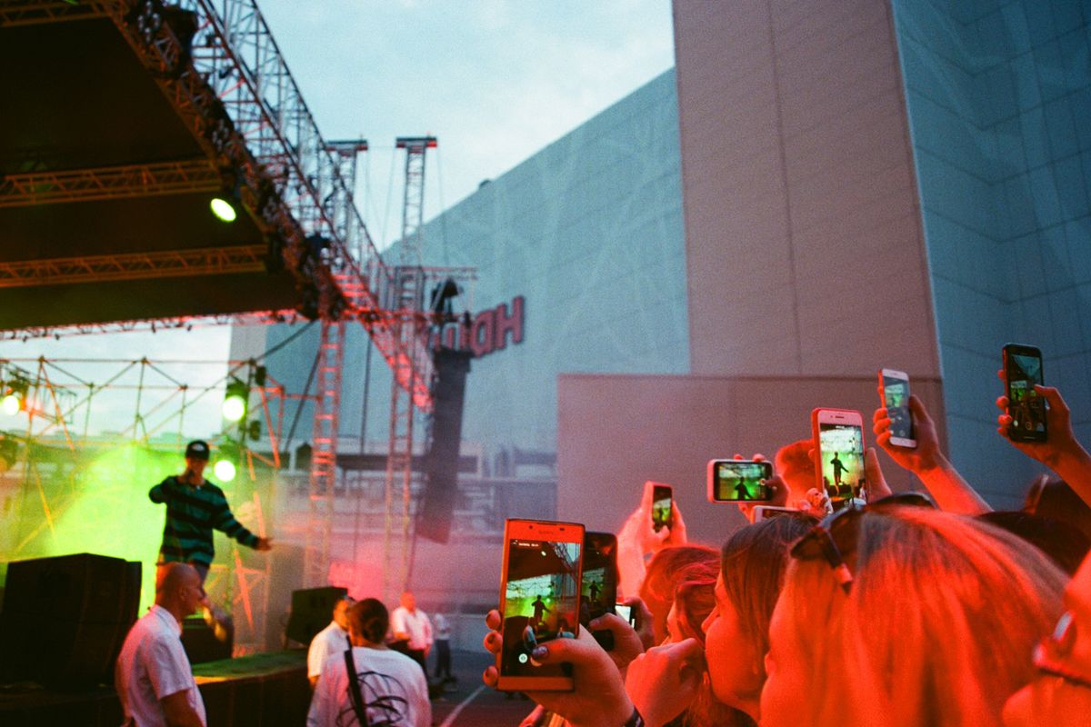 A crowd filming a performer on stage with their phones held up